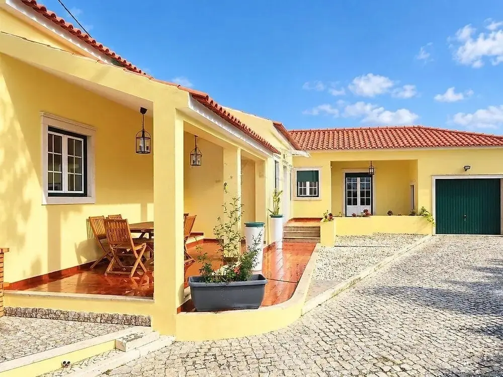 Yellow two-storey house with green shutters in Famalicão, Nazaré